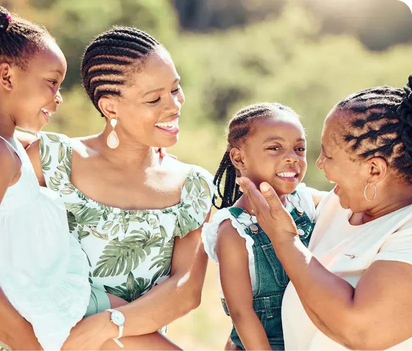 Women and young girls smile and laugh together outdoors.