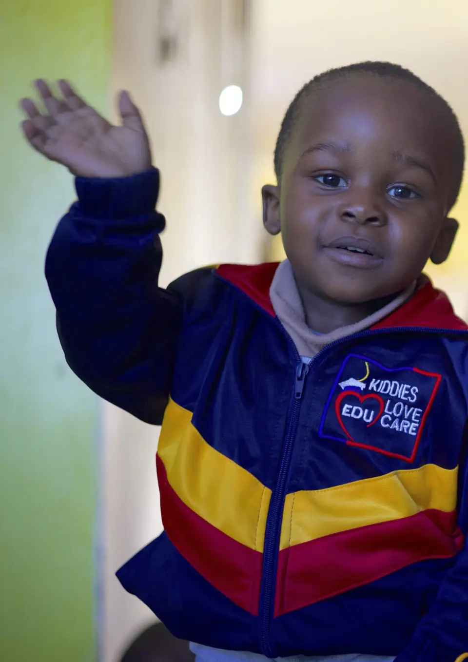 A young boy waving at an early learning centre.