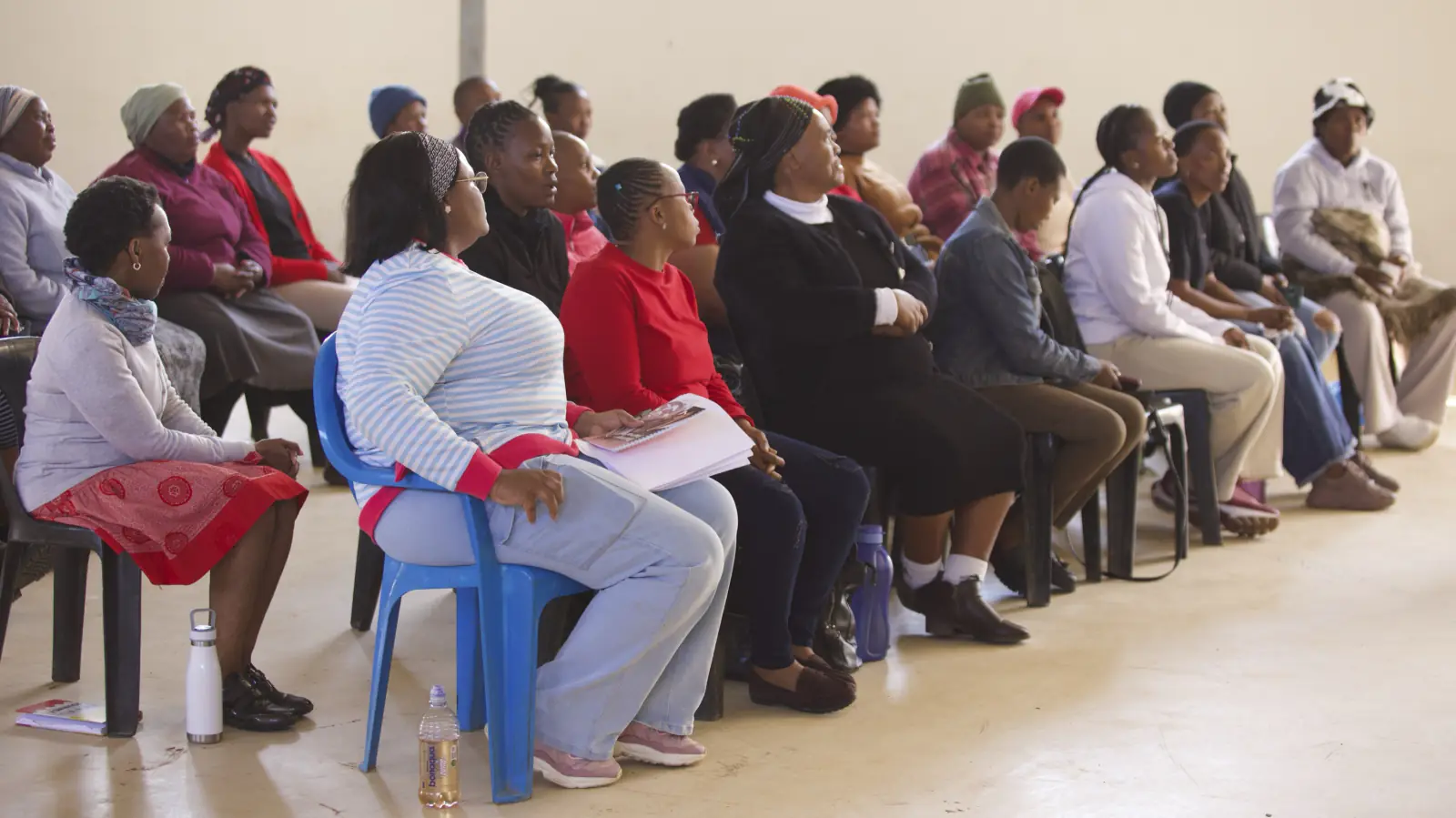 Rows of community members seated on chairs listening at a workshop.