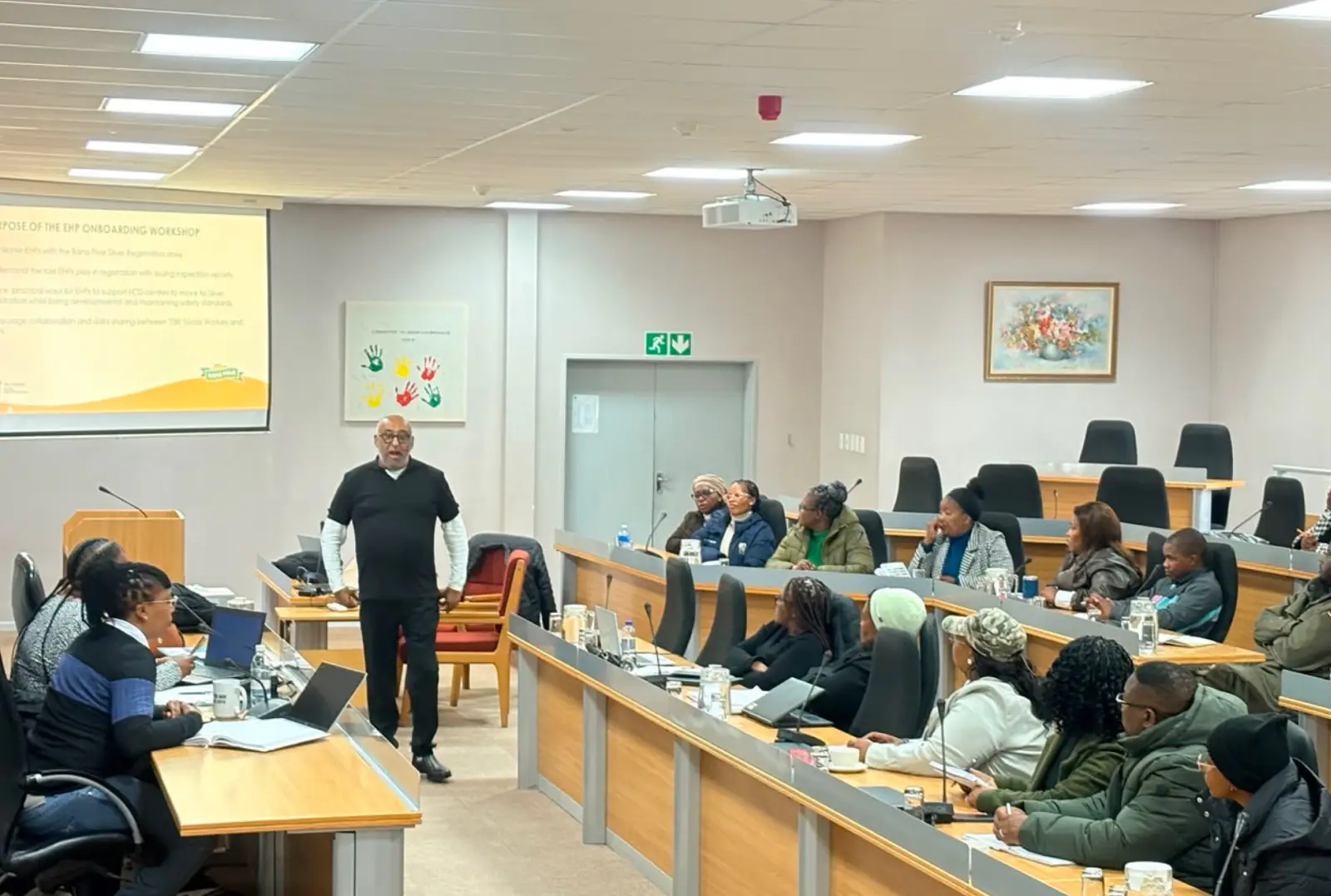 A facilitator presenting to seated participants at an onboarding workshop.